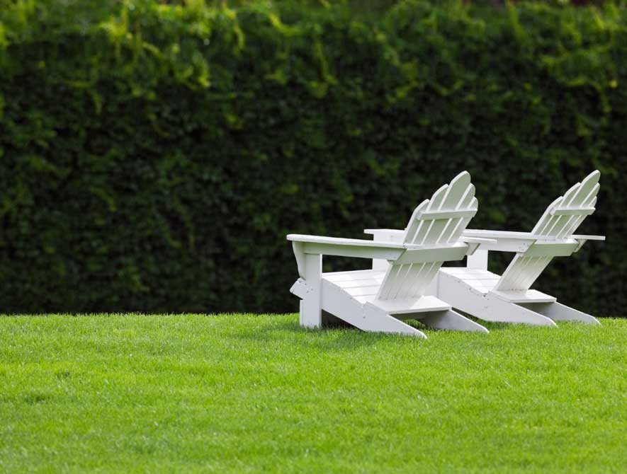 Adirondack chairs on a pristine green lawn.